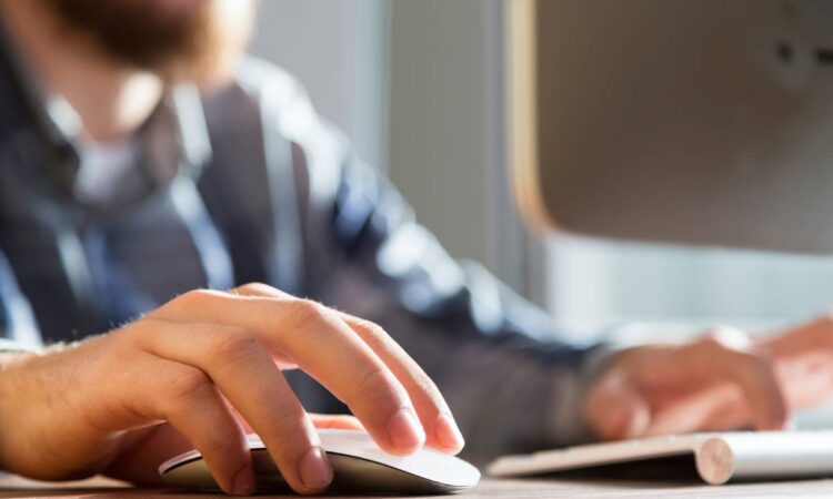 Closeup of man using mouse and laptop.