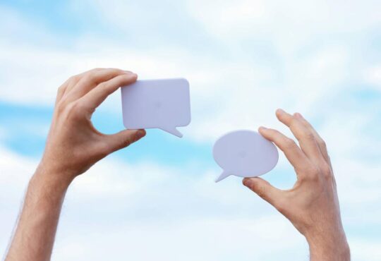 Two hands holding text bubbles.